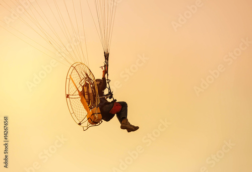 silhouette paraglider flying  with paramotor on sunset