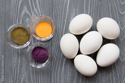 White chicken eggs and color dyes on a gray table. Celebrating Easter