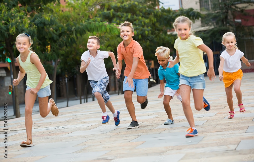 Fototapeta premium kids actively playing and running together on street on summer day