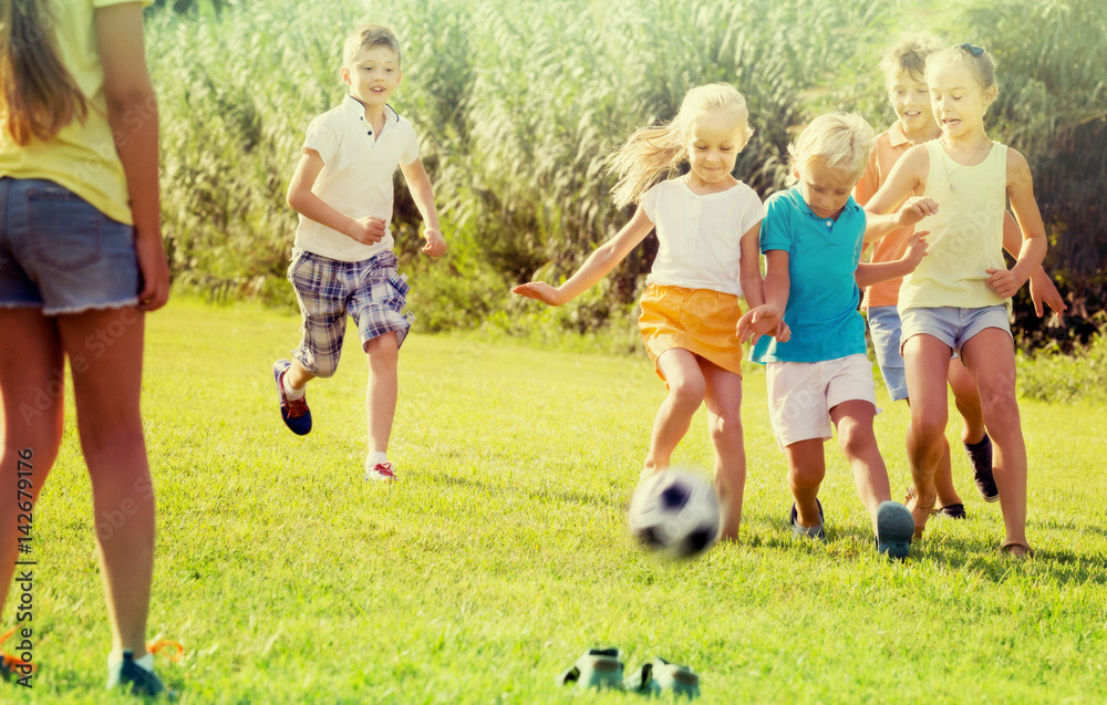 Fototapeta premium kids kicking football in park