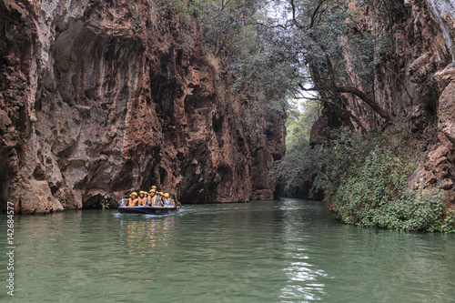 Jiuxiang, China - March 29, 2017: Tourists on a boat in the river in the Jiuxiang scenic area in Yunnan in China. Thee Jiuxiang caves area is near the Stone Forest of Kunming photo
