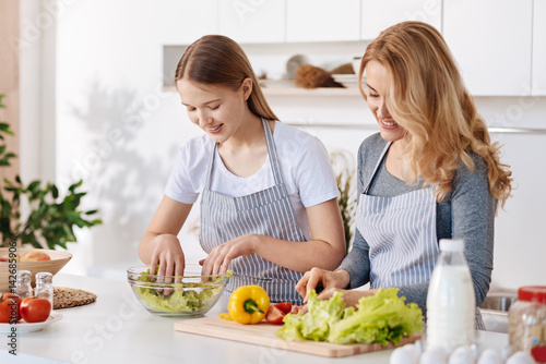 Positive girl and her mother enjoying cooking together