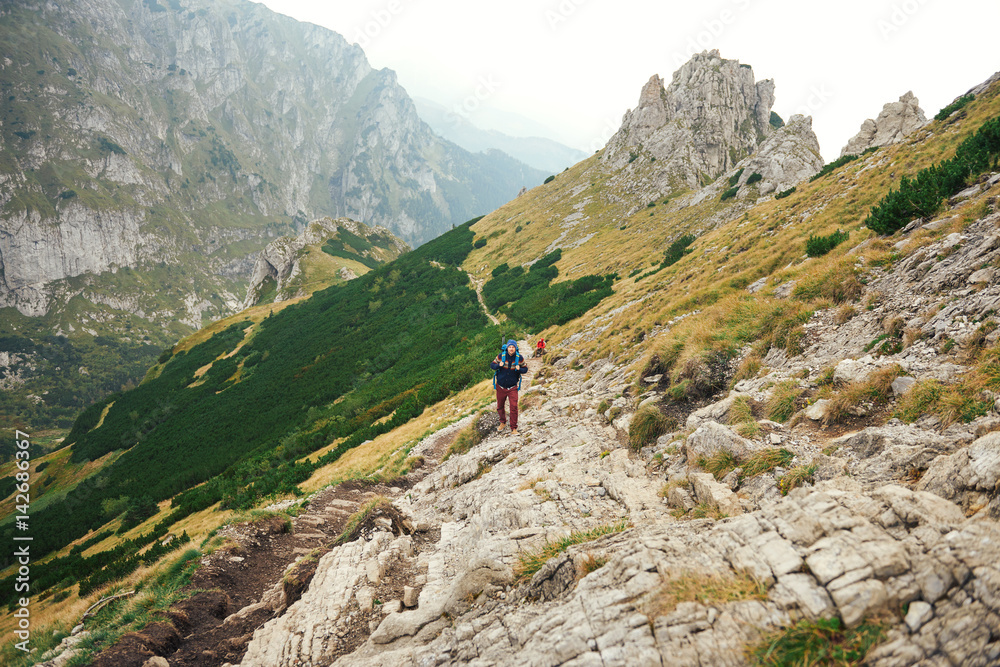 Hikers walking along a trail in rugged mountain terrain