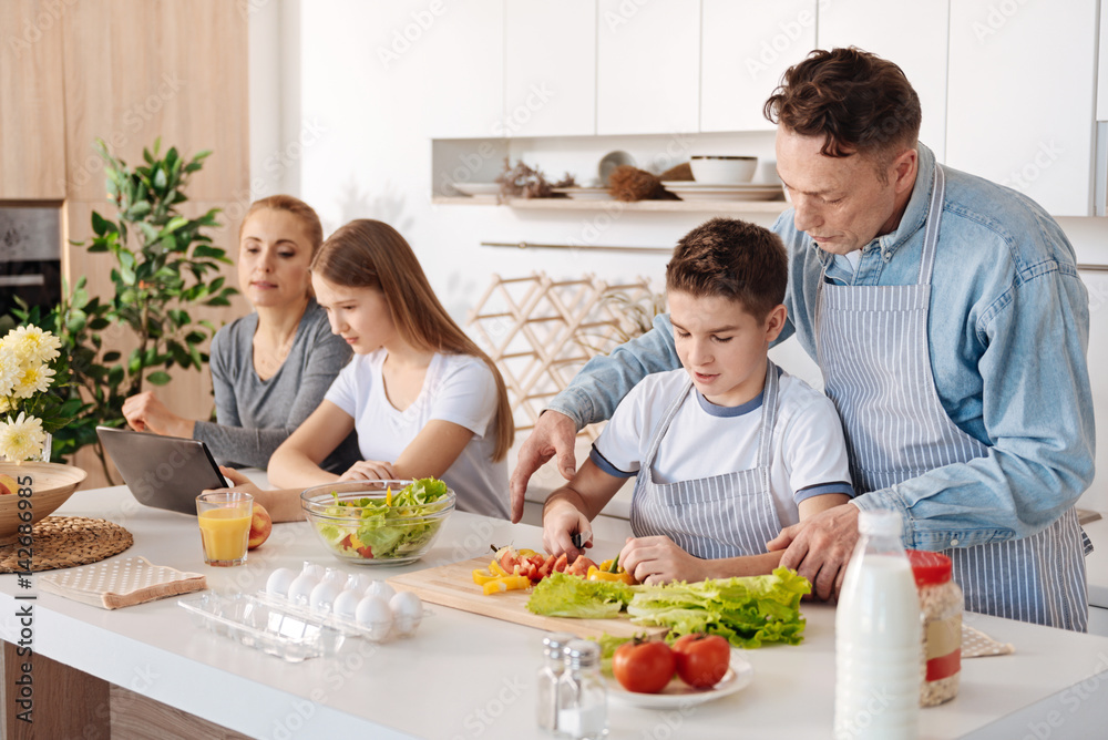 Caring father teching his son to cook