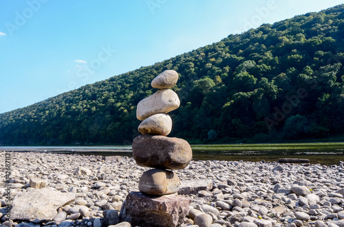 A pile of stones on the bank of the Buller River, with the river in the background and the surrounding high cliffs covered in bush