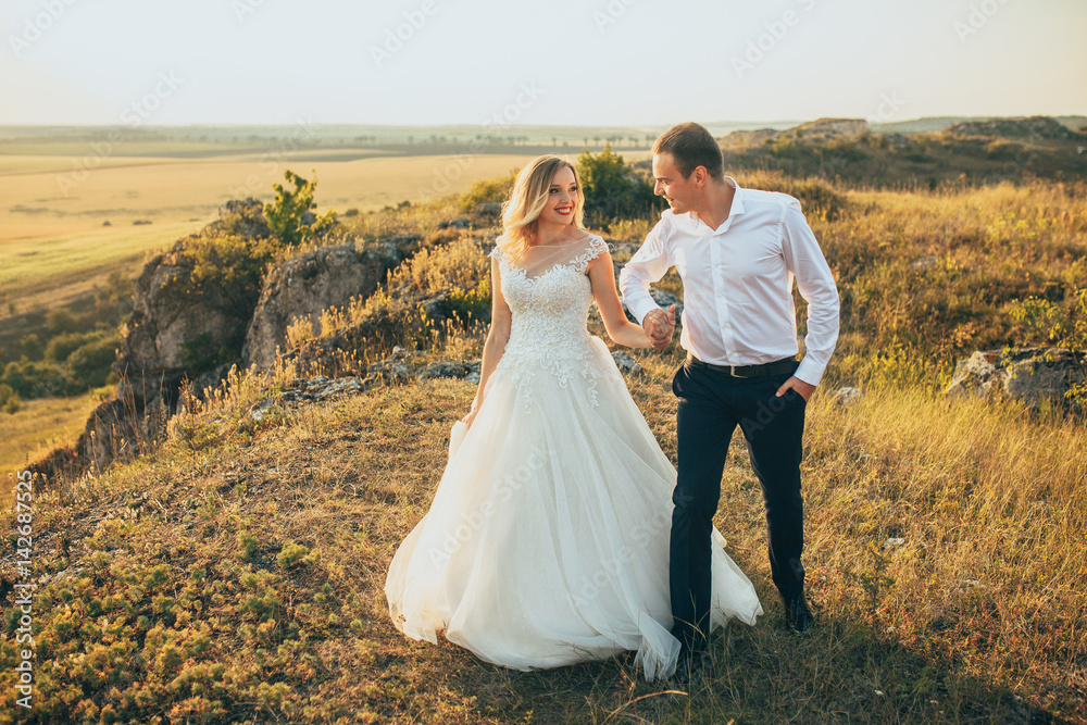 wedding couple running and having fun in mountains in sunset light