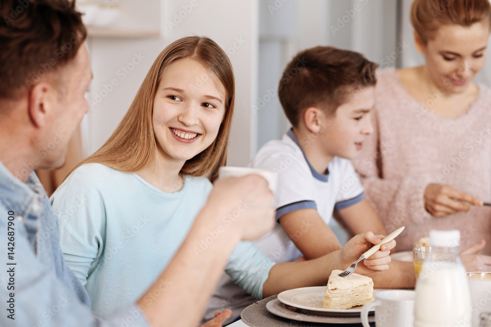 Cheeful girl enjoying dinner with her family Cheeful girl enjoying dinner with her family