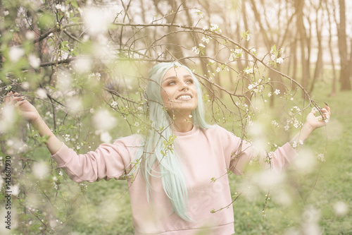 Mint haired young woman in cherry blossom.