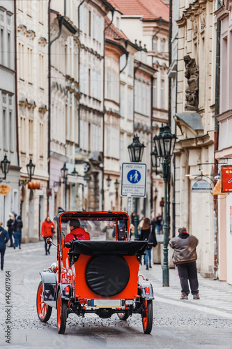 Retro car and unrecognisable people in old European city street