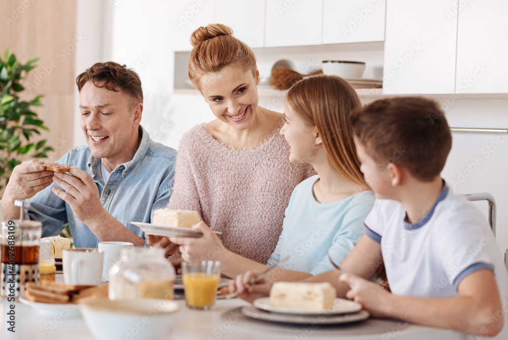 Positive friendly family having breakfast in the kitchen