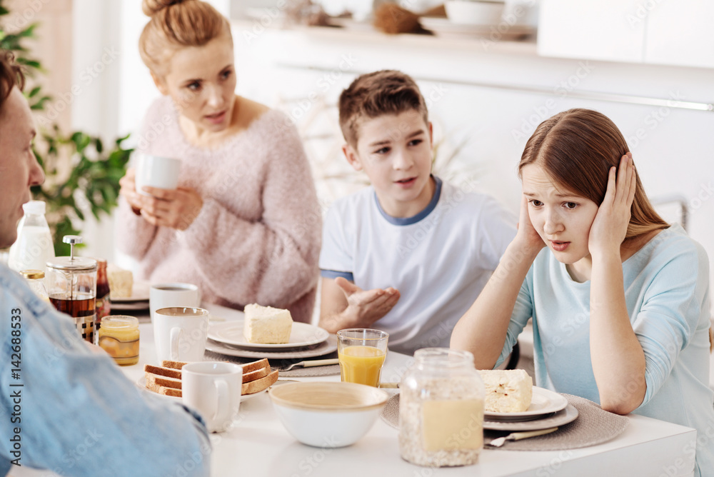 Depressed girl having breakfast with her family