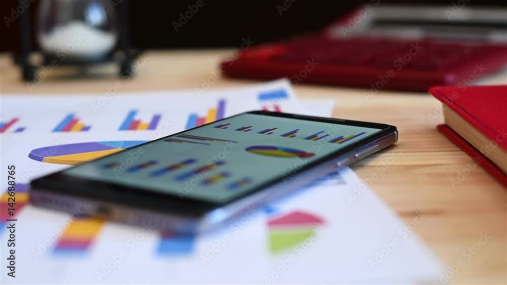 Mobile Phone, Pen, Laptop, Glasses And Paper With Stock Charts On Table. Modern Working Place. Mobile Phone, Pen, Laptop, Glasses And Paper With Stock Charts On Table. Modern Working Place.
