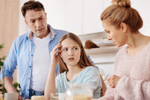 Cheerless moody girl discussing problems with her parents