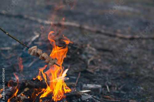 Cooking food at a campfire in the open air.