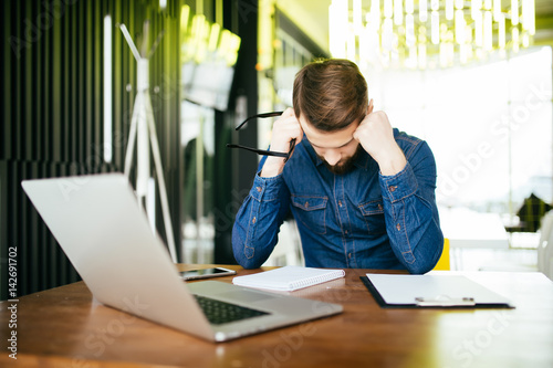 Foto Worried businessman lamenting in front of a computer after a big mistake at offi