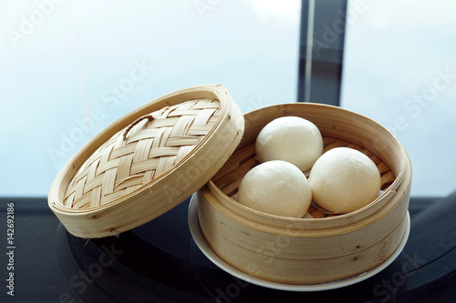 Chinese steamed bun or Chinese steamed yolk custard lava bun in bamboo tray - Traditional Chinese dim sum, Selective Focus.