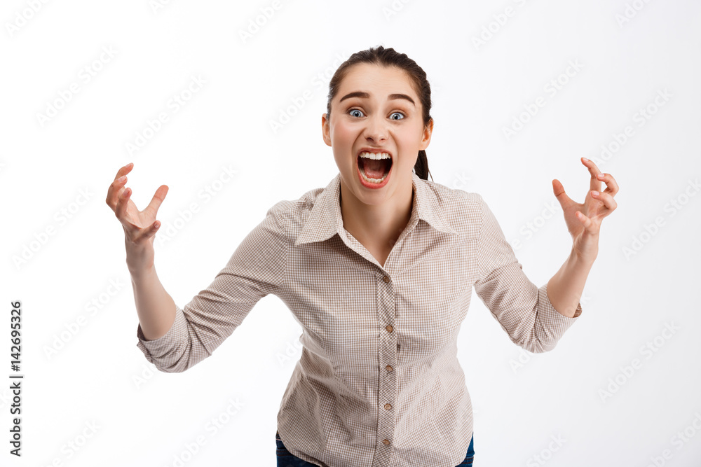 Young beautiful angry crazy brunette businessgirl screaming in camera over white background Young beautiful angry crazy brunette businessgirl screaming in camera over white background