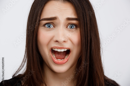 Close up portrait of beautiful scared brunette girl shouting in camera