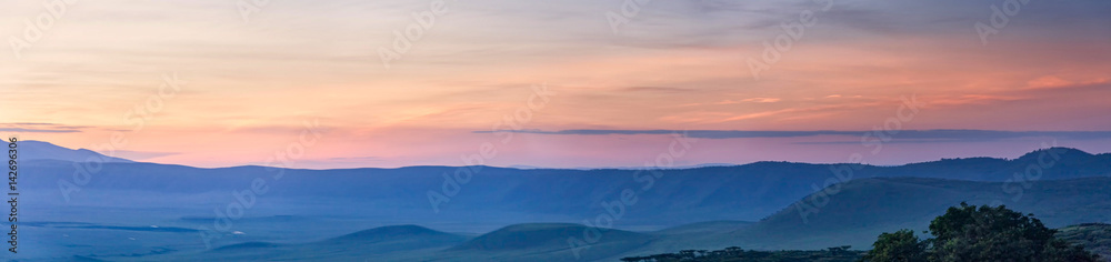 Panoramic view of huge Ngorongoro caldera (extinct volcano crater) against evening glow background at dusk. Great Rift Valley, Tanzania, East Africa.
