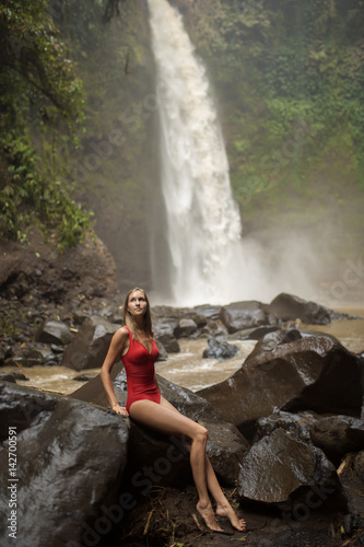 Beautiful woman in red bikini and waterfall.