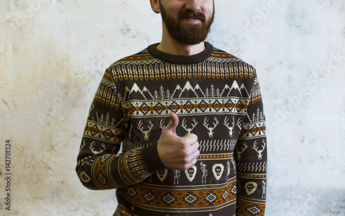 Young smiling attractive man with bearded shows thums up.Portrate of handsome hipster