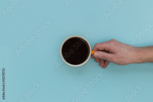 Hand holding coffee cup on bright pink background