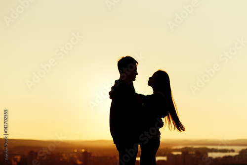 Couple embracing on a roof at the sunset