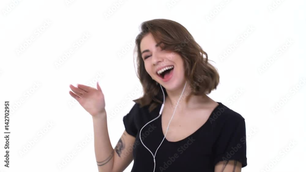 Excited happy teenager girl in earphones enjoying music, dancing and gesturing isolated over white Excited happy teenager girl in earphones enjoying music, dancing and gesturing isolated over white
