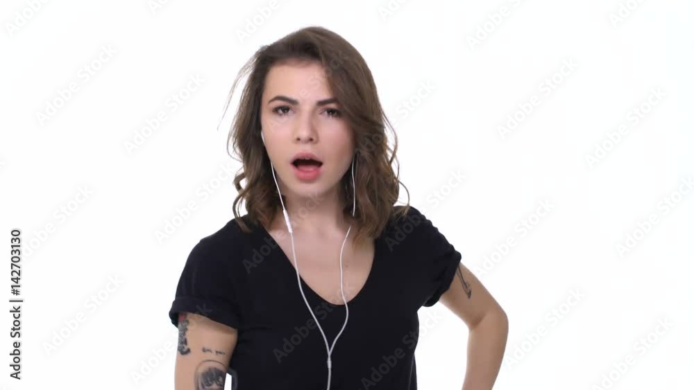 Happy cheerful teenager girl in earphones enjoying music, gesturing with hands and winking isolated over white Happy cheerful teenager girl in earphones enjoying music, gesturing with hands and winking isolated over white