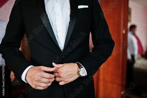 Hands on tuxedo of elegant groom into the room at wedding morning. © AS Photo Family