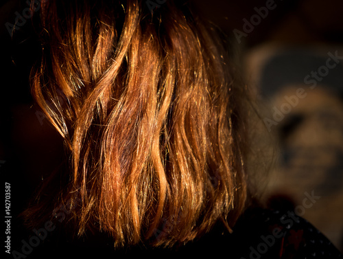 Young woman with vibrant red hair shining in sunlight