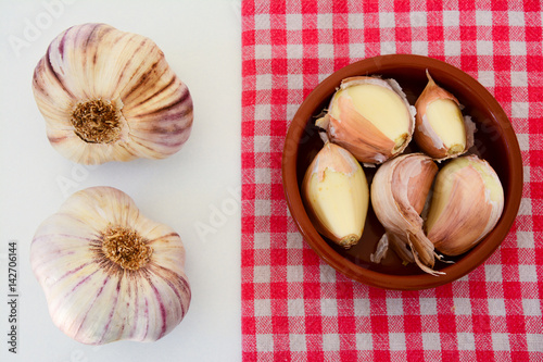 High angle view of garlic and shallot cloves on a rustic towel and white background