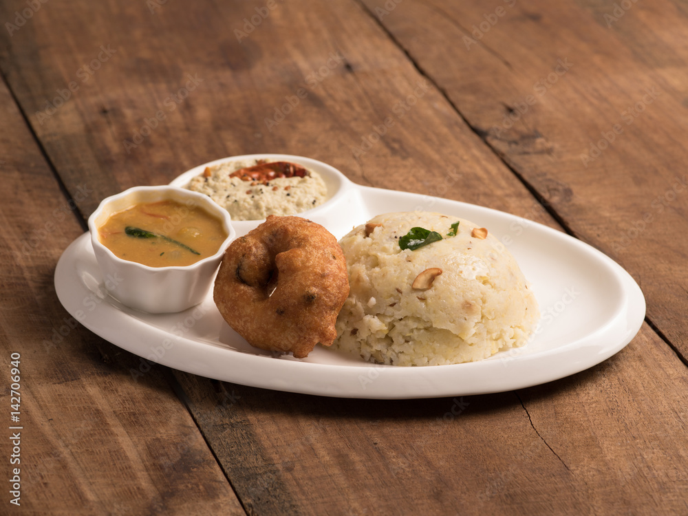 Pongal with vadai sambar and coconut chutney served in a white plate on wooden background