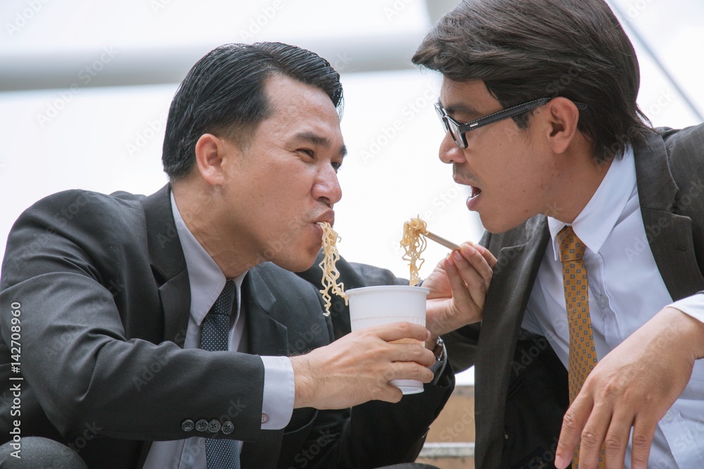 Man is eating instant noodle sadly. His friend is giving him comfort. Man is eating instant noodle sadly. His friend is giving him comfort.
