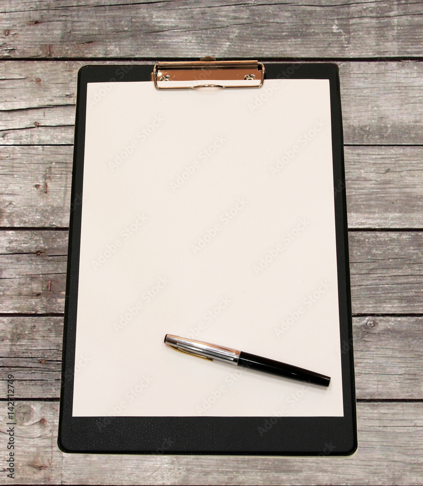 A white sheet of paper with pen on a wooden table made of Board A white sheet of paper with pen on a wooden table made of Board