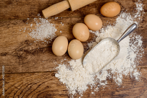Flour, eggs and rolling pin on wooden table