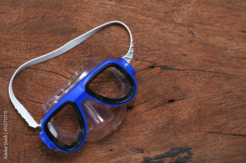Diving mask goggles put on the hard wood brown color surface background represent the skin diving equipment 