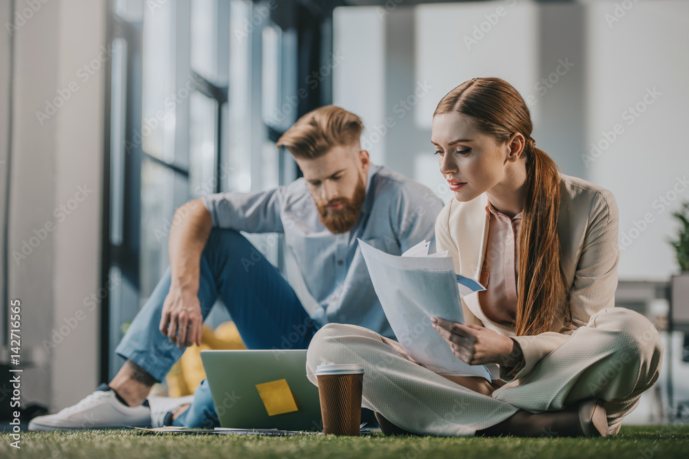 Young businessman and businesswoman working with documents and laptop Young businessman and businesswoman working with documents and laptop