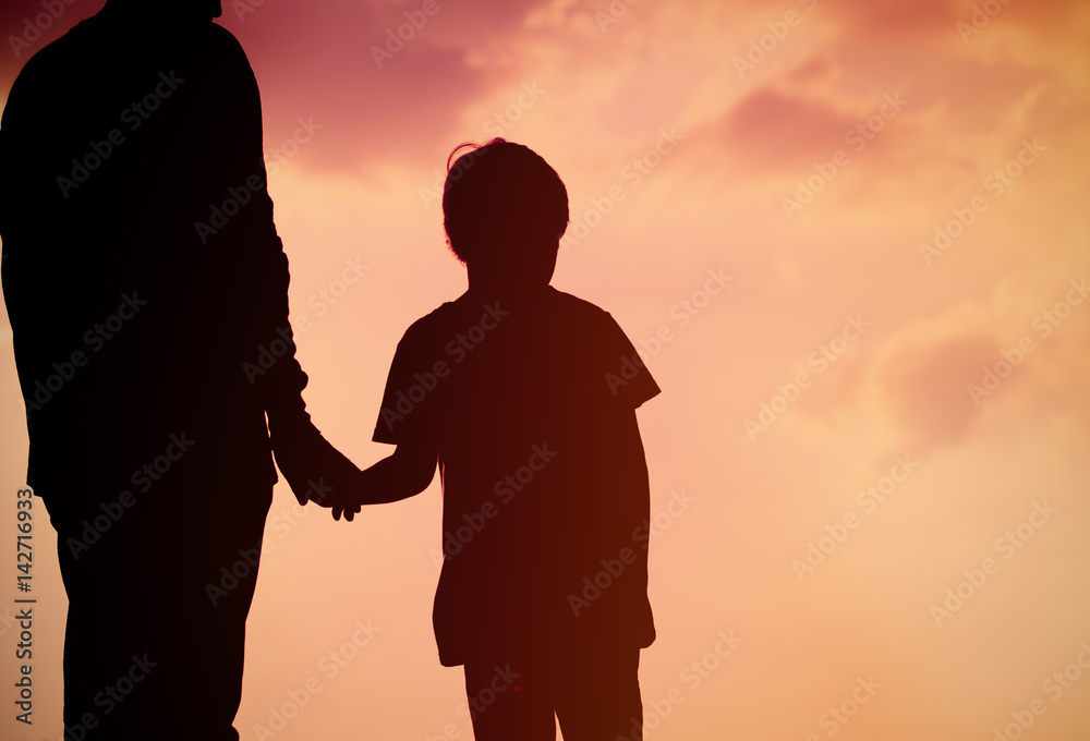 silhouette of father and son holding hands at sunset