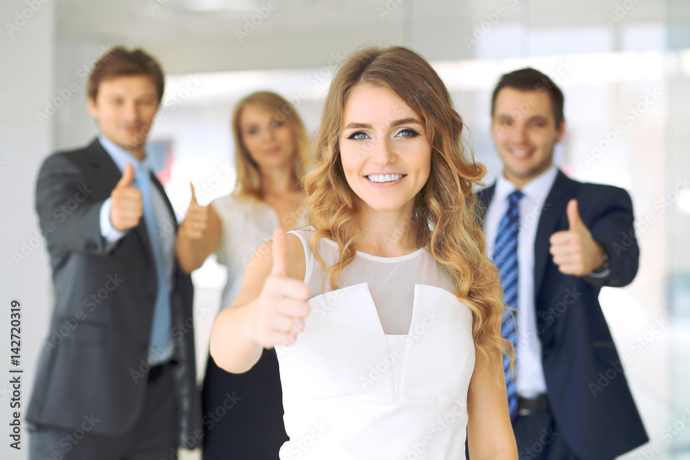 Successful young business people showing thumbs up sign while standing in office interier Successful young business people showing thumbs up sign while standing in office interier