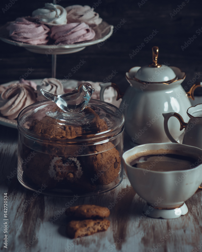 A Glass jar with cookies and a cup on a wooden table on dark background. Vintage Style A Glass jar with cookies and a cup on a wooden table on dark background. Vintage Style