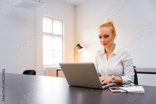 Beautiful business woman using her lap top at the office