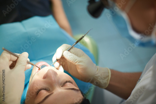 The dentist begins to examine the oral cavity of a beautiful girl
