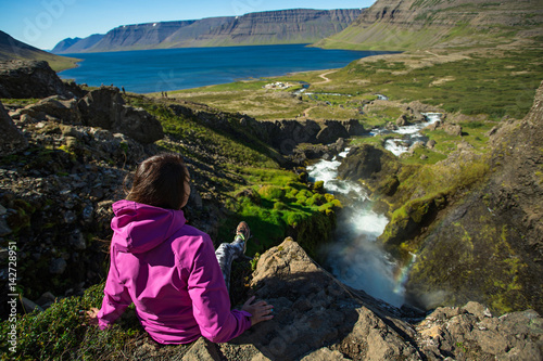 Girl sitting on the edge of a mountain. Dynjandi waterfall, Iceland.