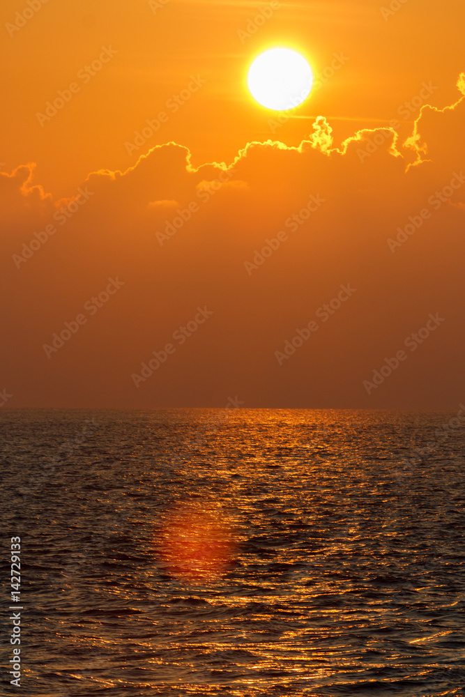 Beautiful sunset over sea with reflection in water, colorful clouds in the sky