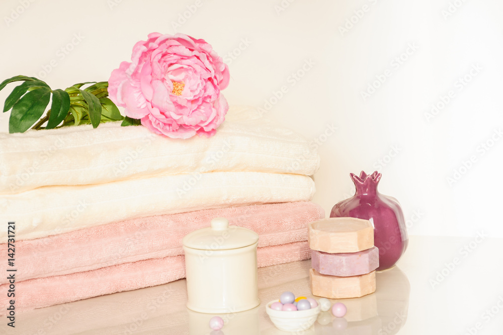 Bath setting in white and pink colors. Towel, aroma oil, flowers, soap. Selective focus, horizontal.