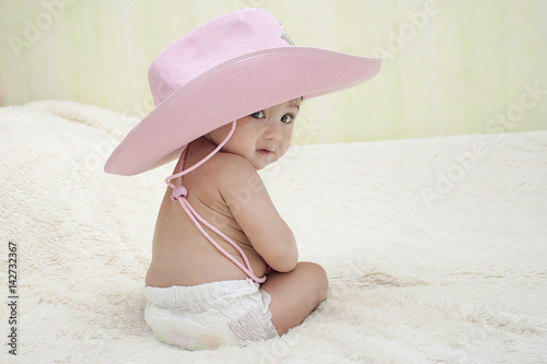 baby sitting in a pink cowboy hat