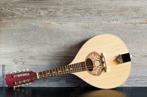 Front view of a reclined wooden flatback mandolin on a black table with a weathered wood background photo
