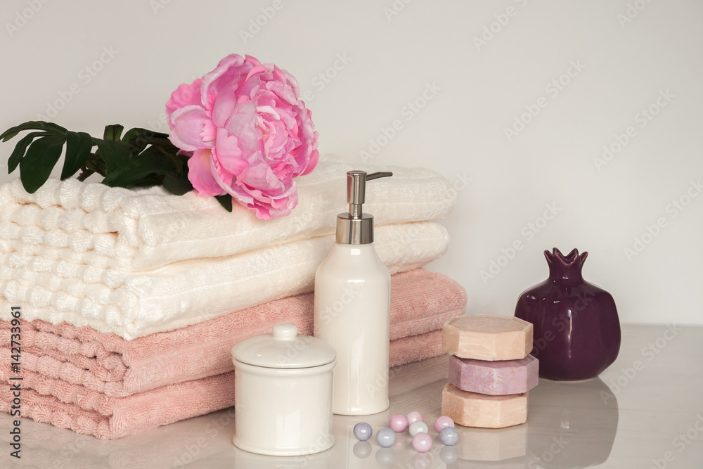 Bath setting in white and pink colors. Towel, aroma oil, flowers, soap. Selective focus, horizontal. Bath setting in white and pink colors. Towel, aroma oil, flowers, soap. Selective focus, horizontal.