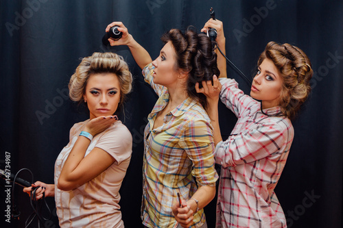 Three young girls making hairdress to each other